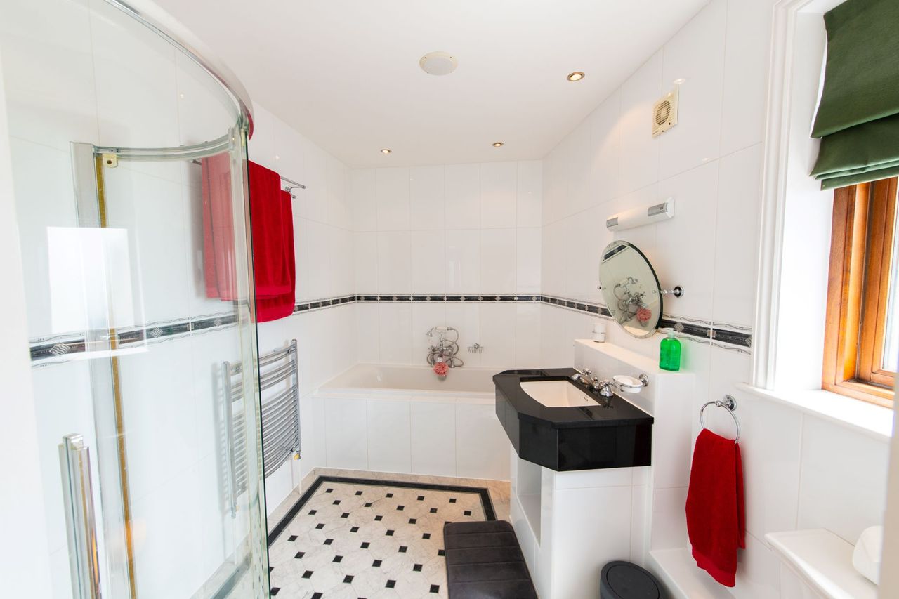 En suite bathroom with black sink top and walk-in shower with white tiles all round