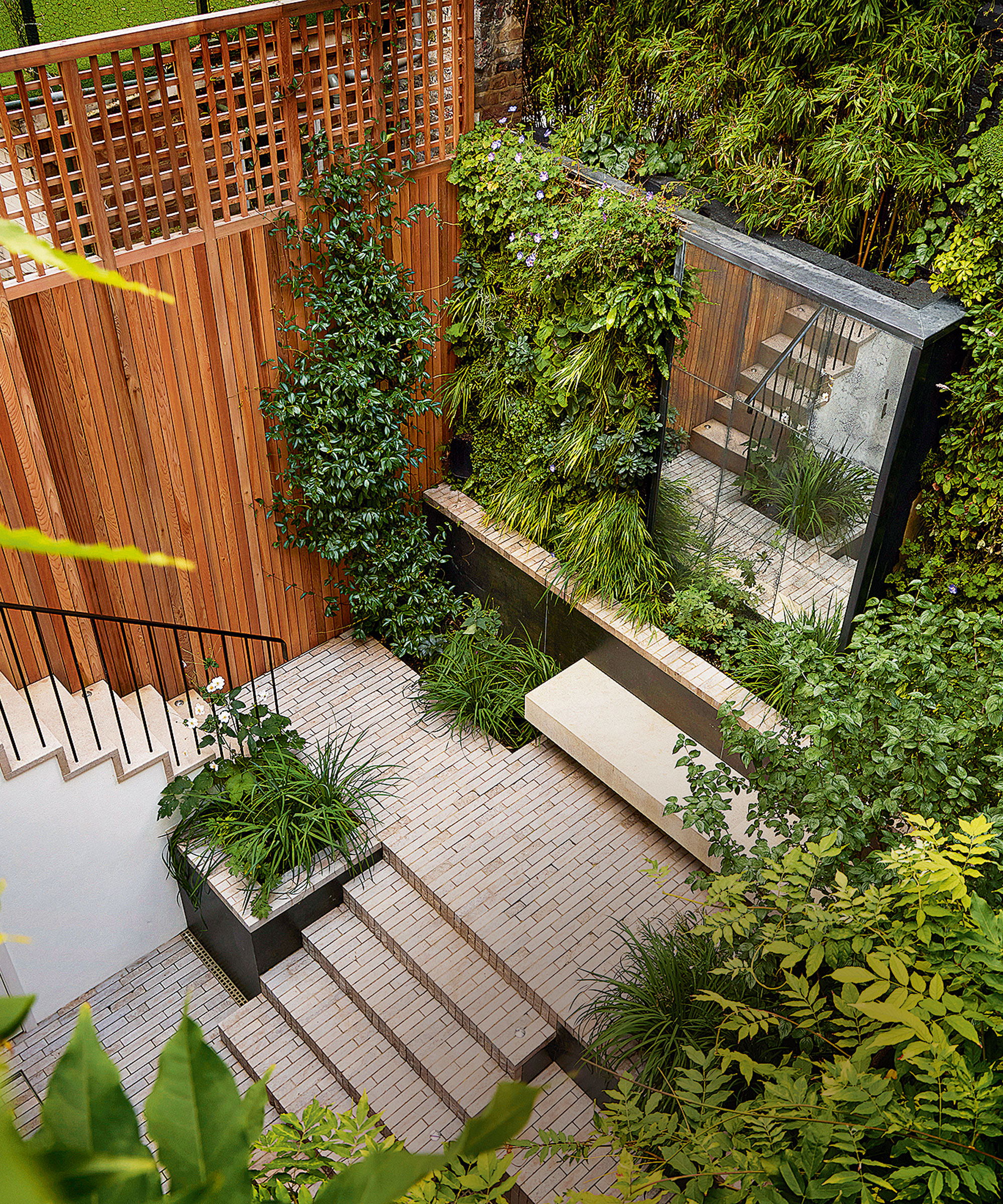 Small garden with striking vertical design, mirrored doors, plant wall, wooden paneling, brick steps, planters