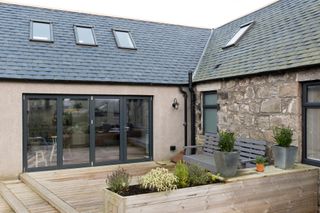 Designing a single storey extension: The back of the cottage has a courtyard area leading back into the house through grey bi-folding doors