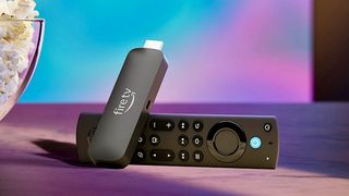 Amazon Fire TV Stick and remote on a table beside a bowl of popcorn