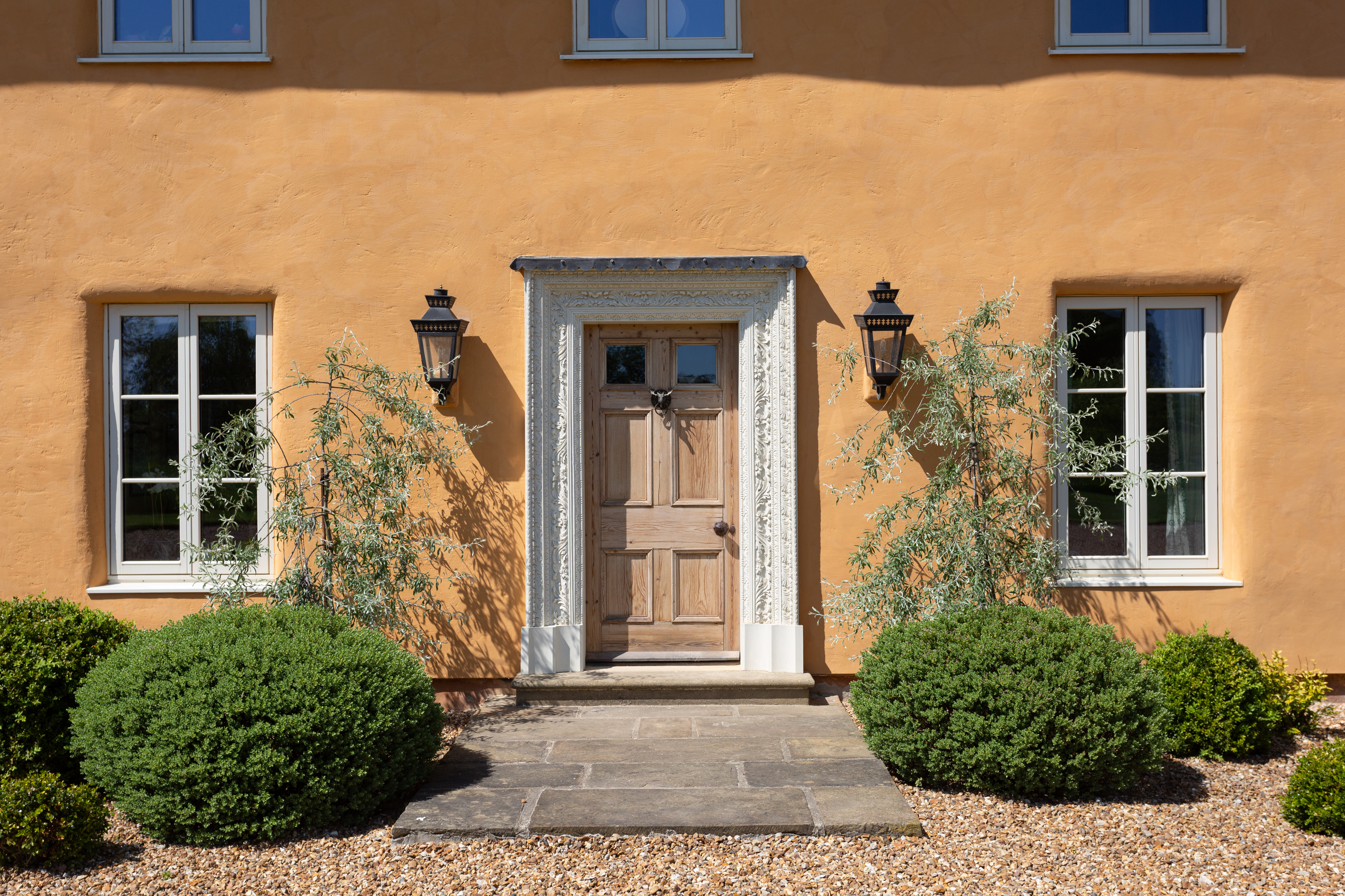 Details of the Lime House in Yorkshire. It is yellow, with a red tiled roof surrounded by green fields. Inside, wood panelled walls contrast with stone fittings and floors for a very farmhouse feel.