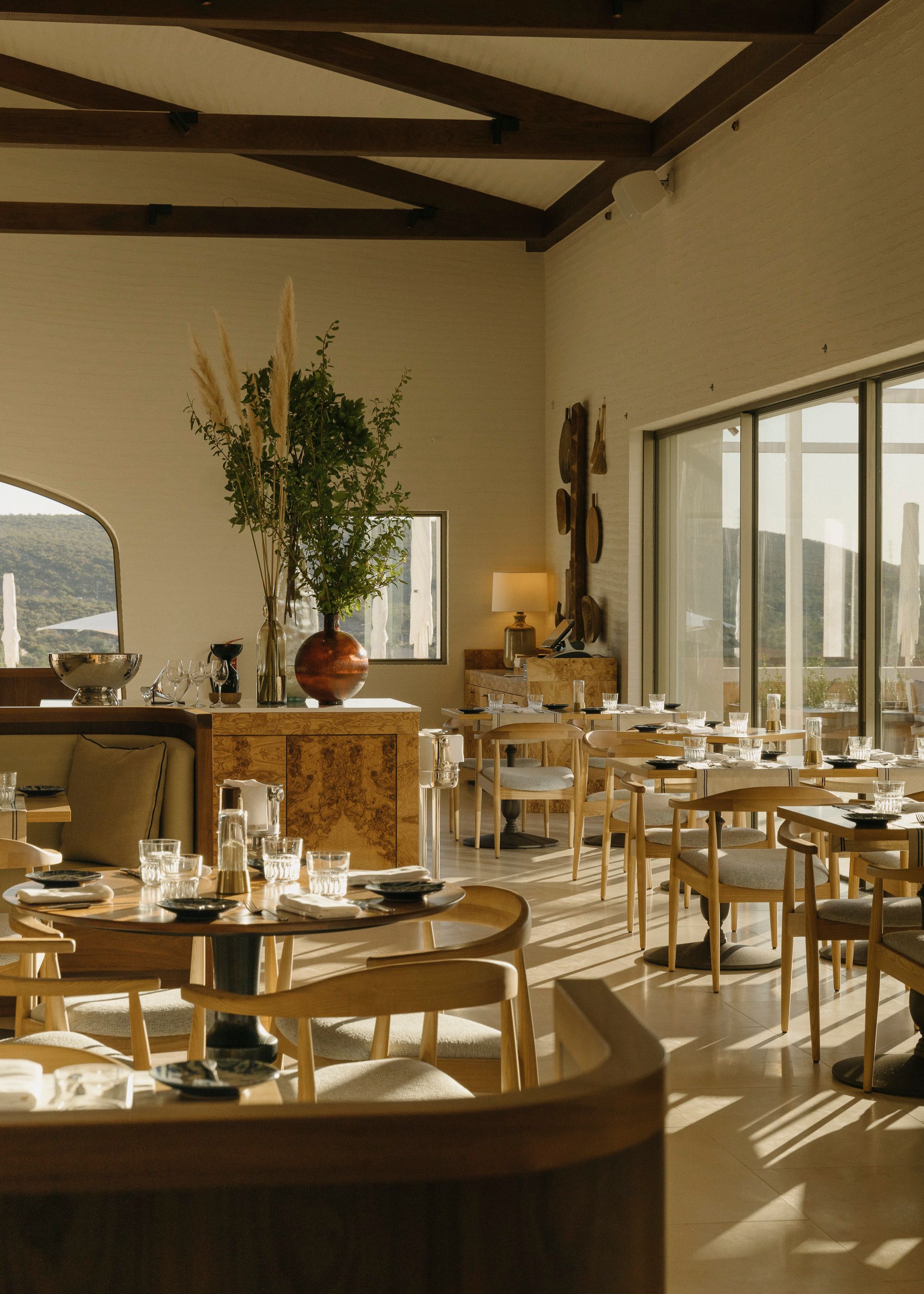 A hotel restaurant known as the Ombria in Faro, Portugal. In the space, there are beige colored tables and chairs with lots of wooden textures