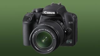 Canon EOS Kiss F camera with lens against a green background