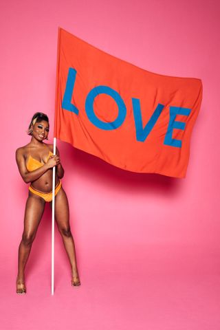 Love Island 2022 star Indiyah Polack holding up an red flag with the word love written on it.