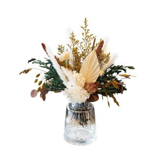 A white, beige, and blue dried flowers bouquet in a glass vase