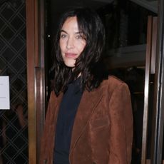 Alexa Chung wearing a brown suede blazer with a black dress and black high-heel sandals