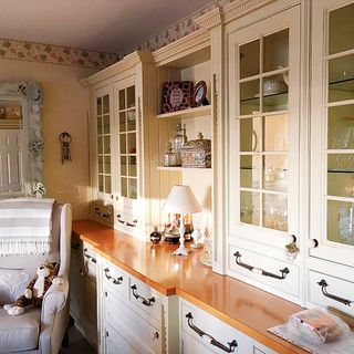 A traditional cream kitchen with built-in cabinetry and grey upholstered chair with plush toy