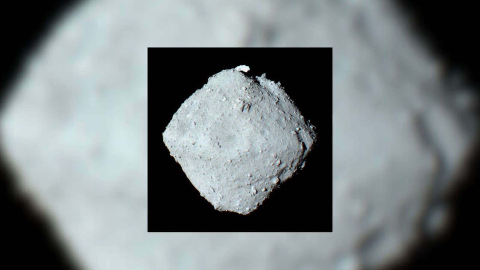 A gray asteroid rock in front of a dark background