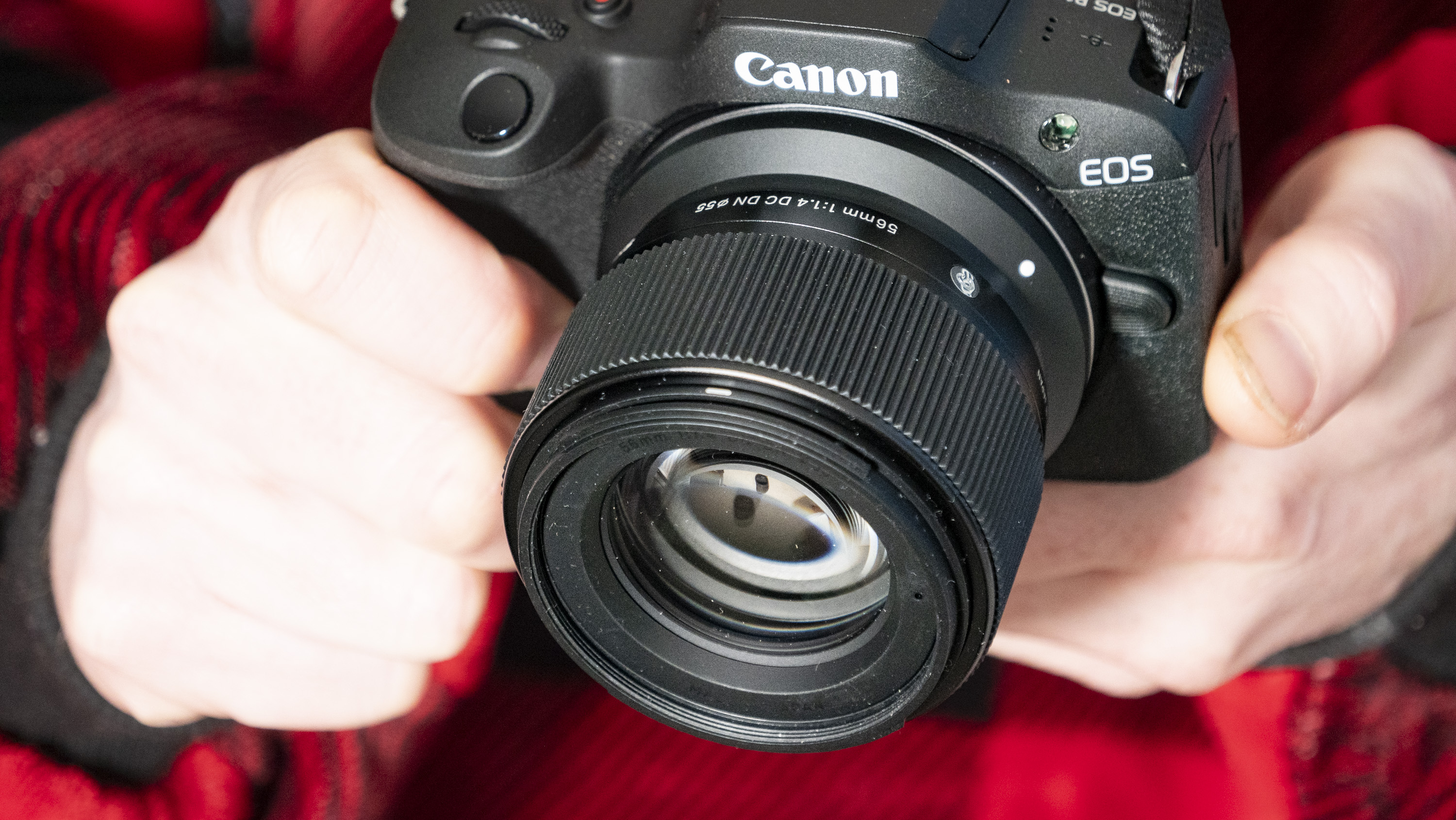 Sigma 56mm F1.4 DC DN Contemporary lens in the hand attached to a Canon EOS R100