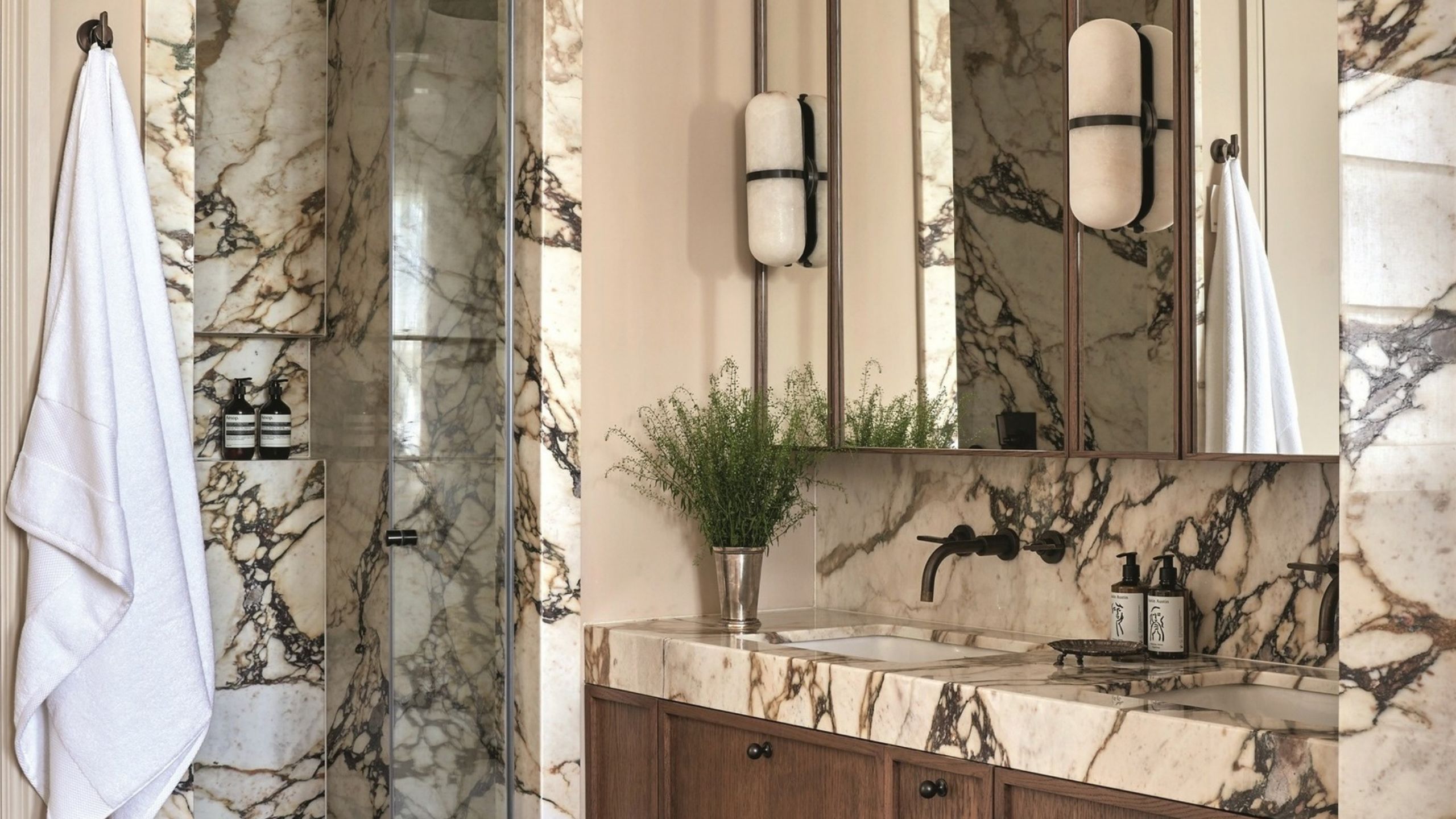 marble bathroom with shower and vanity with timber vanity and medicine cabinet with wall sconce and white towel hanging