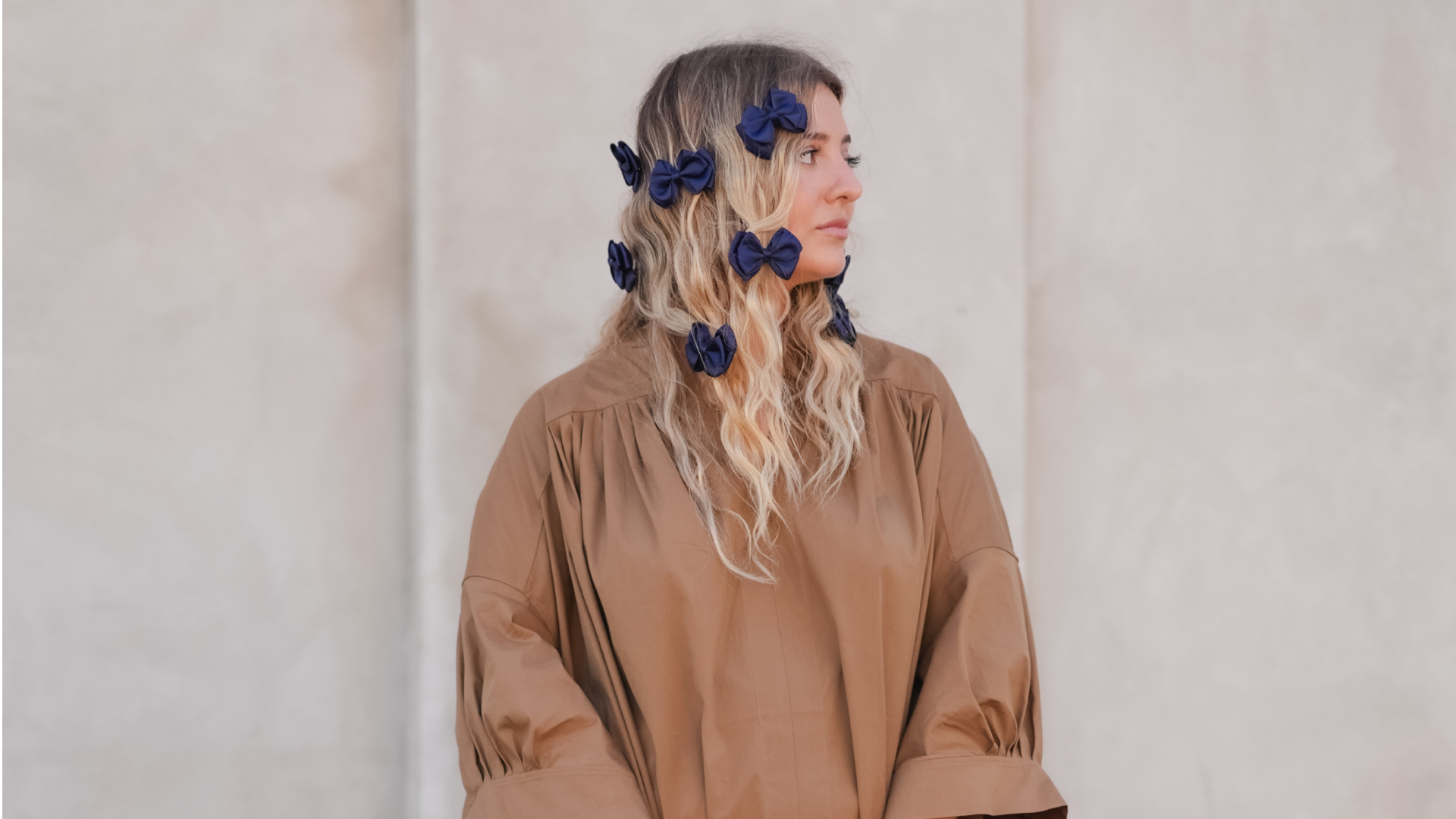 Woman with bows in her hair posing with face away from the camera.