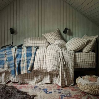 Neutral plaid linen bedding on a double bed piled high with cushions