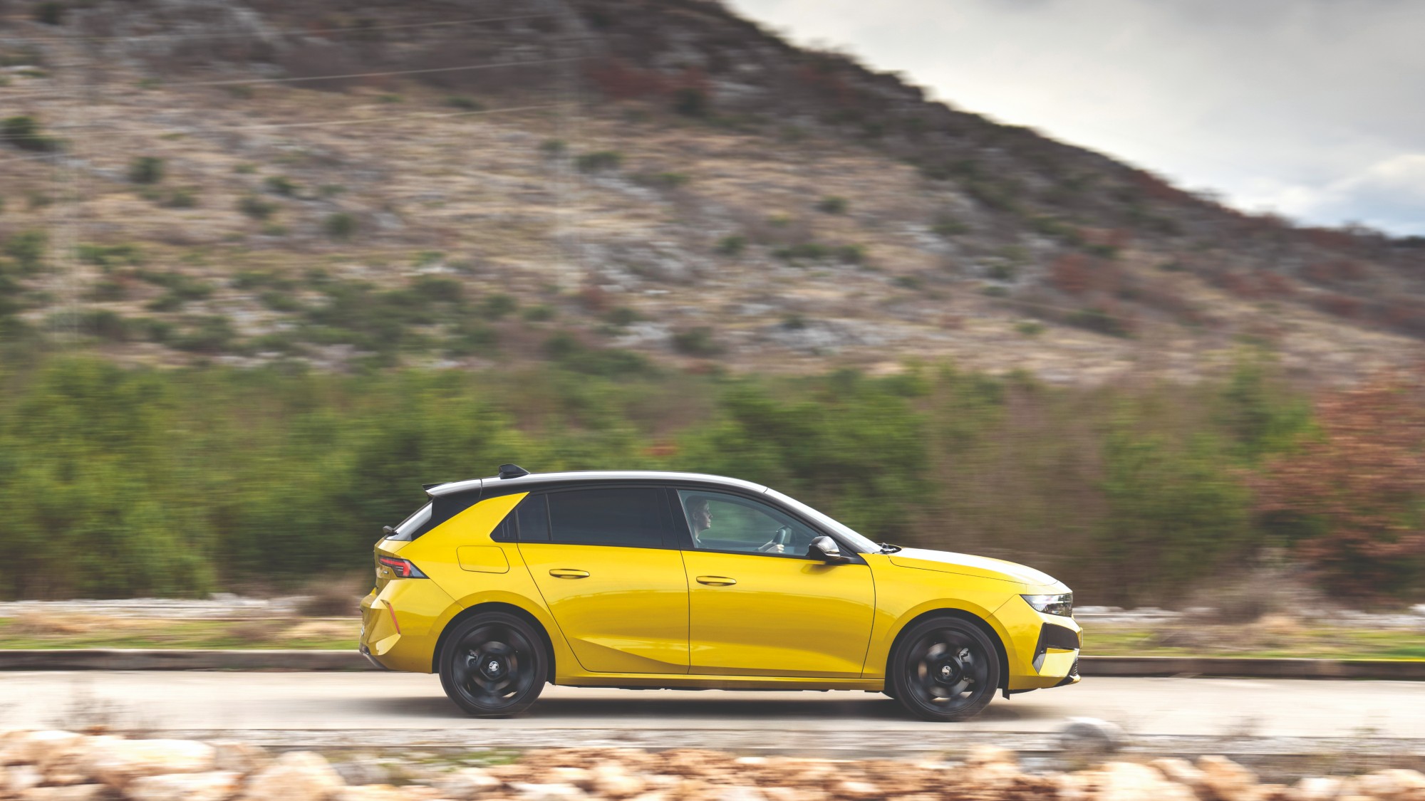 Yellow Vauxhall Astra 2026 driving with a mountainous background