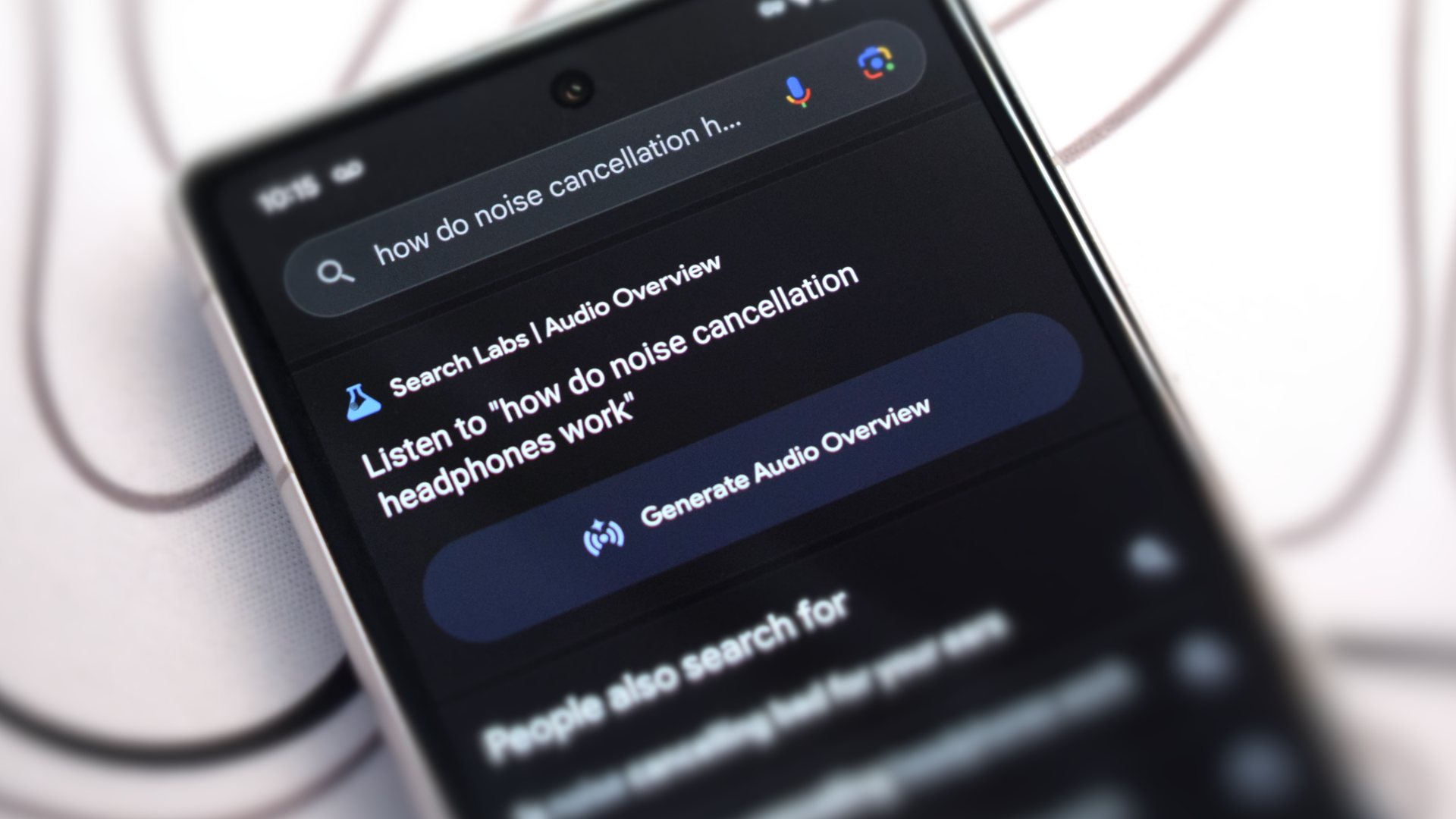 Google Pixel 7a showing Google Search results page, including the new Audio Overview feature which uses Google Gemini to generate short-form podcast-like audio overviews of search results presented by two virtual hosts.