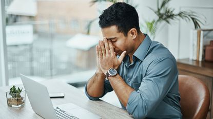 man worried sitting at desk by laptop for missed the tax deadline