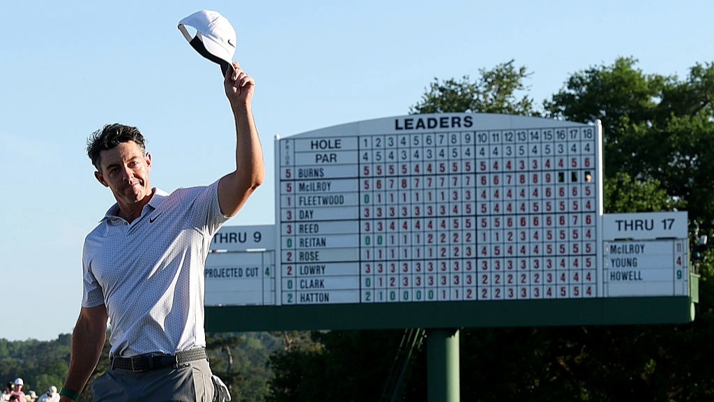 Rory McIlroy raises his cap to acknowledge the crowd, with the scoreboard in the background, after leading the Masters 2026 by six shots at the halfway stage.
