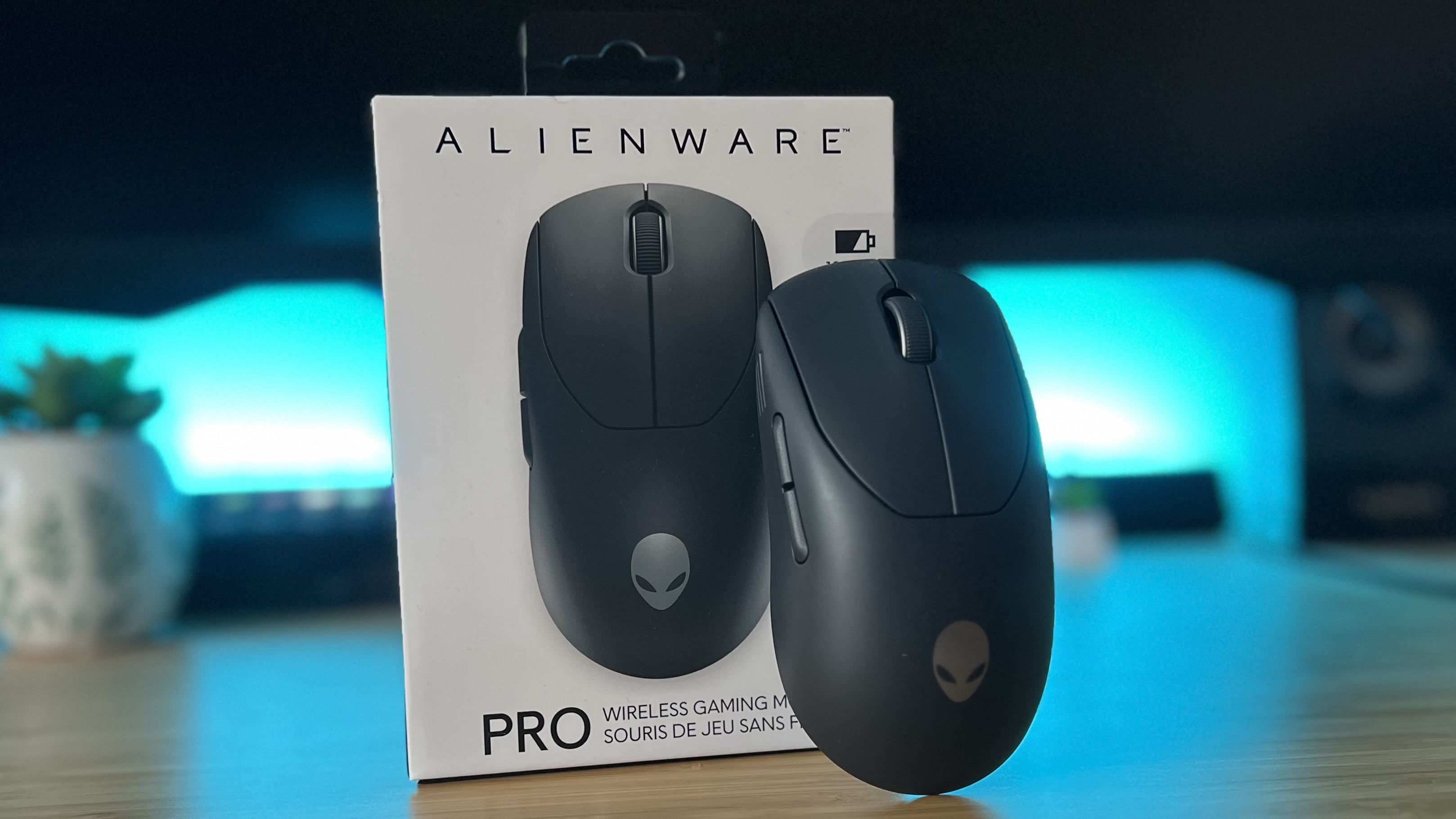 Alienware Pro Wireless gaming mouse leaning against packaging in a PC setup