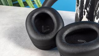 A pair of black Edifier WH950NB over-ear headphones photographed against a blue background