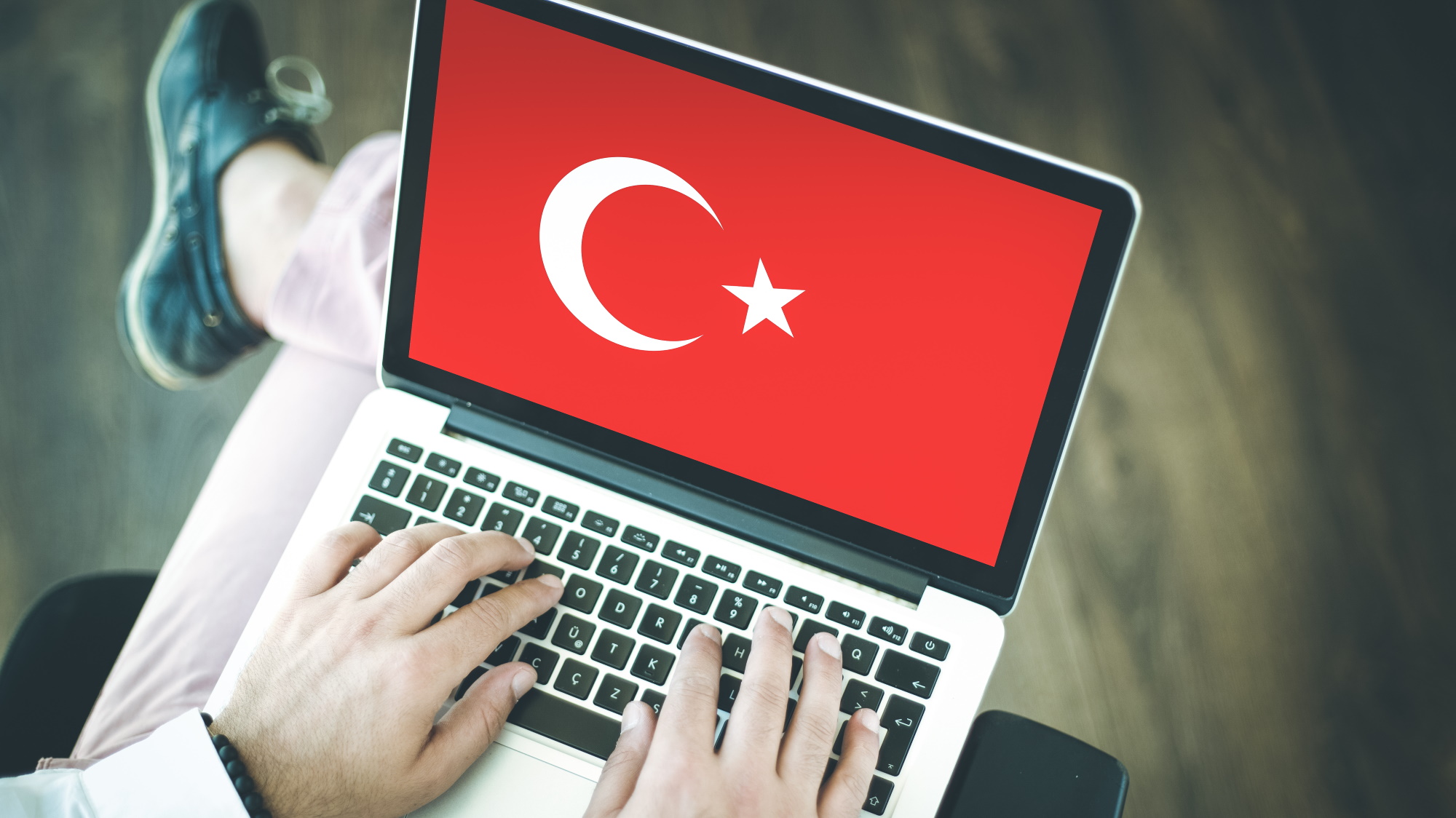 Orang yang menggunakan laptop dengan bendera Turki di layar