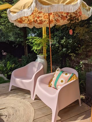 Pink freshly painted IKEA SKARPÖ chairs in yard with sunny print parasol and turf surround
