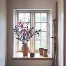 A window with a vase of flowers and a burning candle on the windowsill
