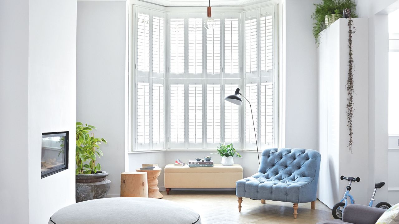 White living room with white shutters and pale blue chair