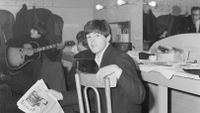 Paul McCartney of The Beatles holding a copy of Disc magazine in a dressing room at the Gaumont Cinema, Doncaster, 10th December 1963. Behind him are George Harrison (1943 - 2001, left) and John Lennon (1940 - 1980, centre)