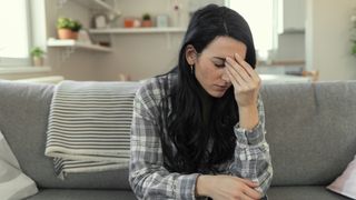 woman sitting on her couch feeling sick