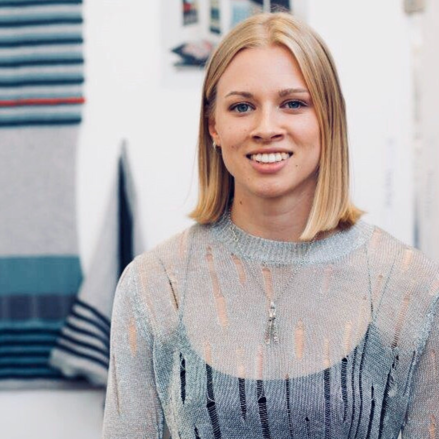 A woman with short bonde hair in a textured gray sheer sweater