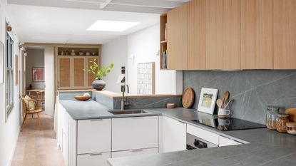 Narrow kitchen with wooden and white cabinets, grey worktop and white walls