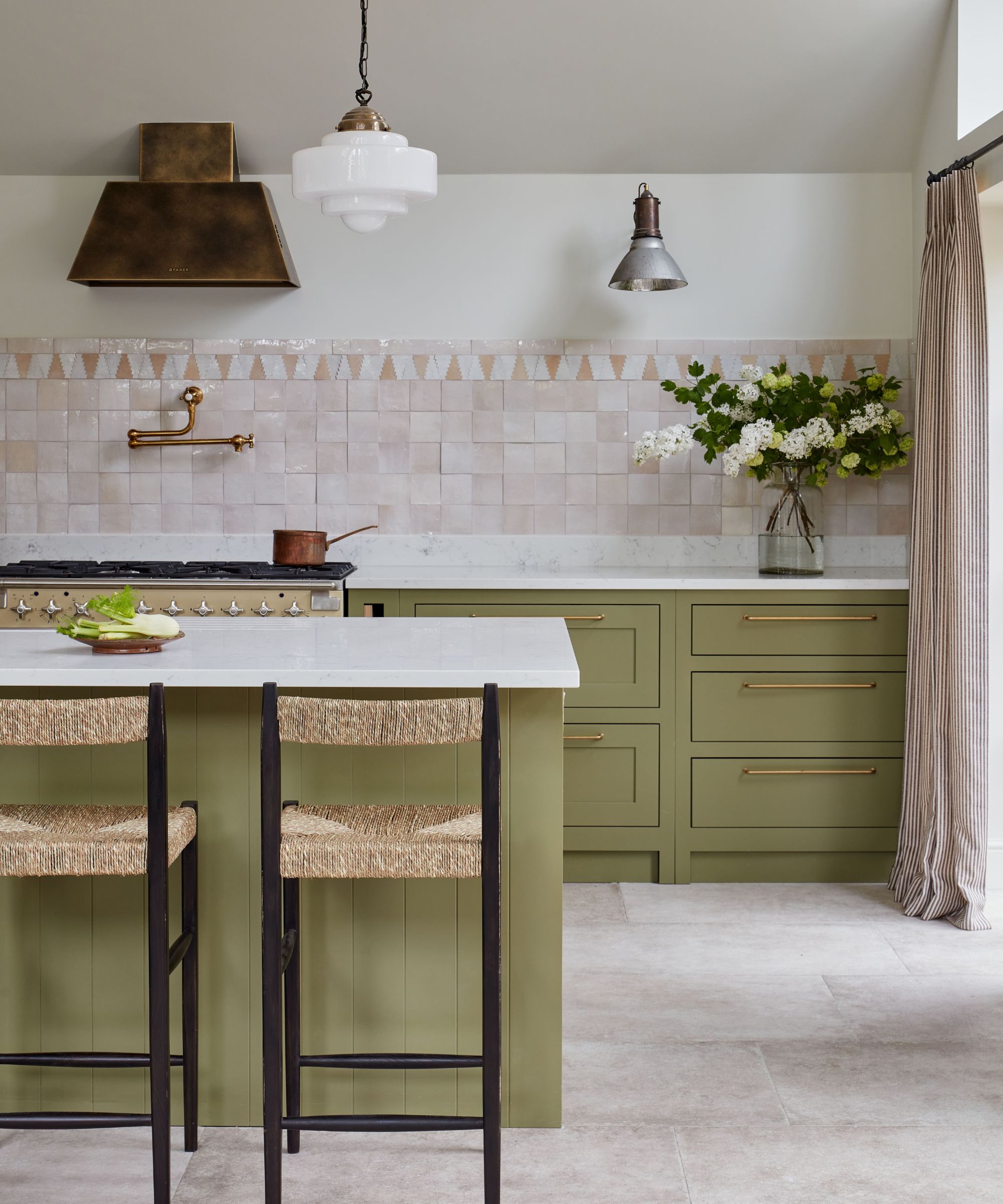 green and pink kitchen with vintage lighting and rattan bar stools at the island