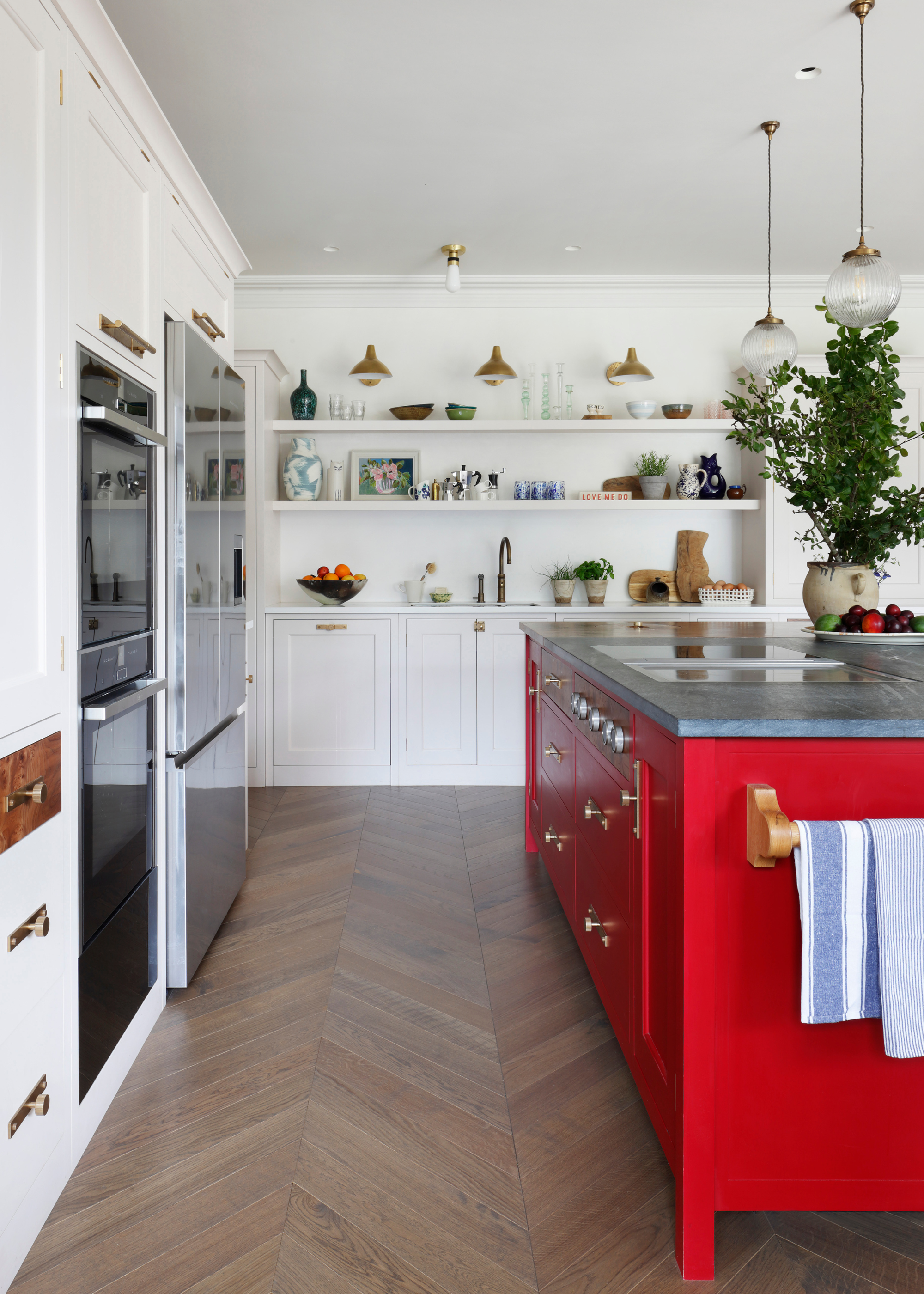a modern kitchen with parquet flooring and a red island and white cabinets