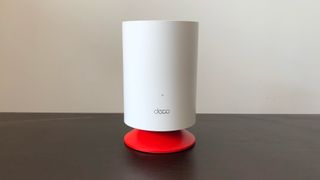 TP-Link Deco Voice X20 system on a dark wood table next to a white wall