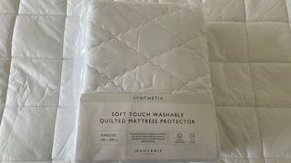 John Lewis Soft Touch Washable Quilted Mattress Protector packaging on the bed