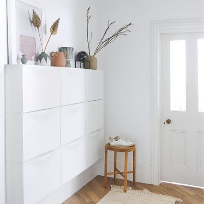 White painted hallway with white storage unit for shoes and brown wooden floors
