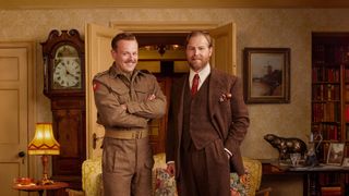 Callum Woodhouse in an army uniform as Tristan and Samuel West in a brown suit as Siegfried stand together in Skeldale House in All Creatures Great and Small