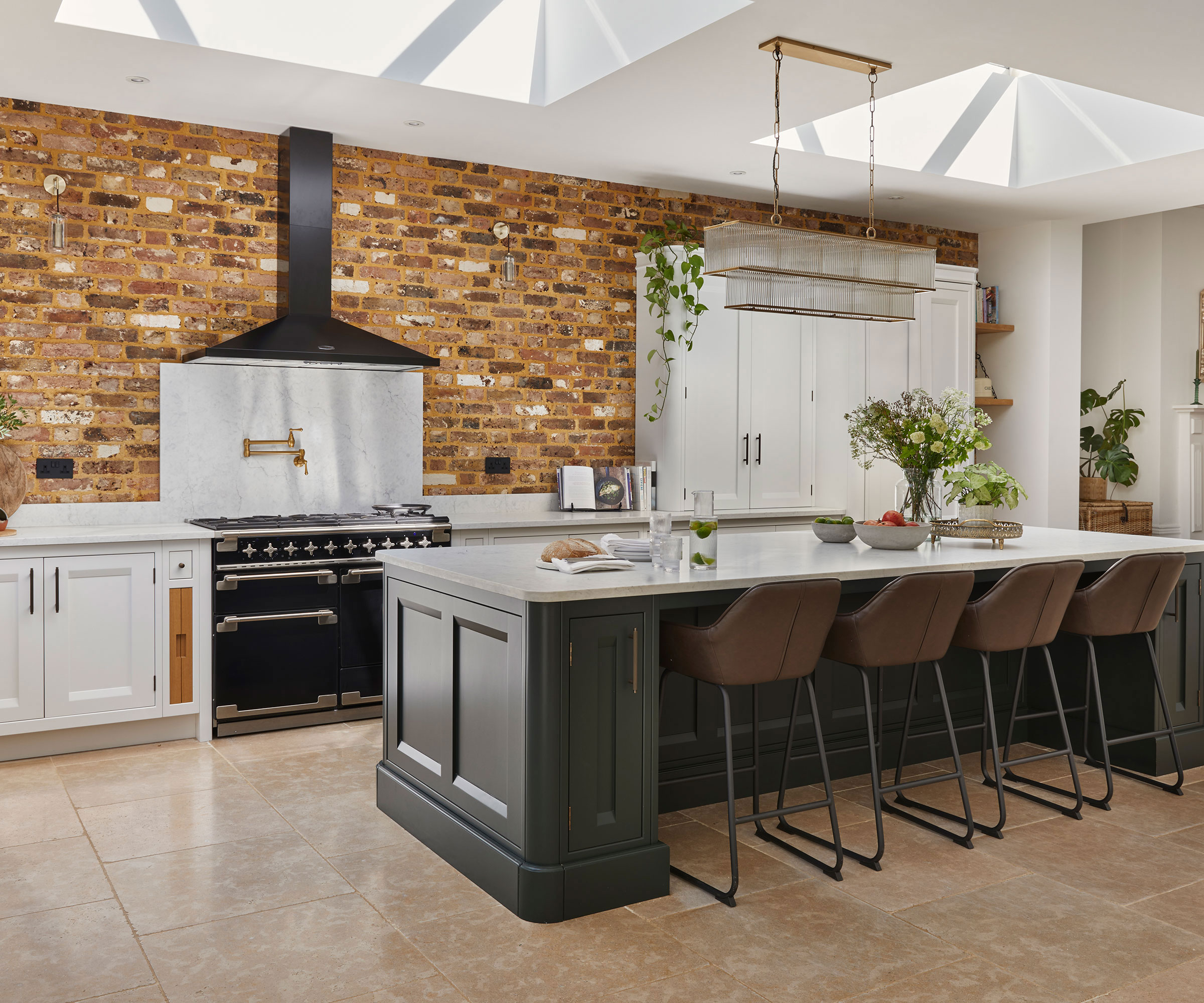 brass pot filler on stainless steel splashback in Shaker kitchen with exposed brick walls