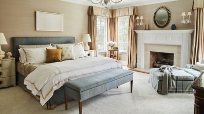 An example of bedroom storage ideas showing a bed with a pale blue headboard and matching upholstered storage bench 