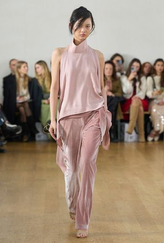 how to wear velvet is shown in a photo from Eudon Choi's fall 2024 runway show with a model wearing a pastel pink funnel neck top with matching velvet trousers and heels