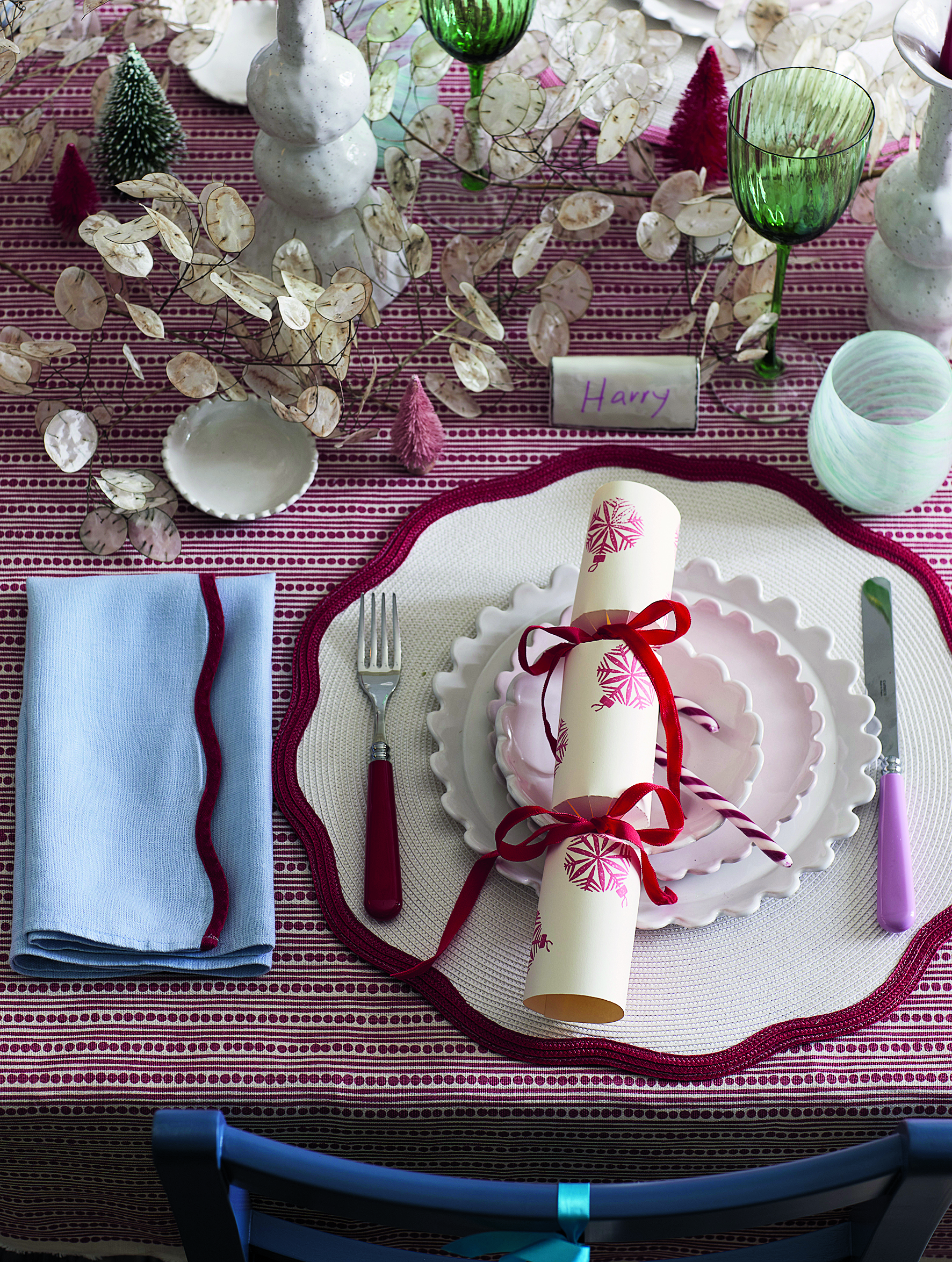 Christmas place setting with handmade cracker, candy cane, red and white tablecloth, honesty garland