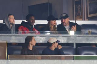 Taylor Swift and Travis Kelce in their box at the Yankees game wearing black hats and black jackets