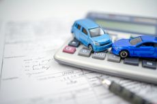 Car insurance symbolised by two toy cars hitting each other on top of a calculator