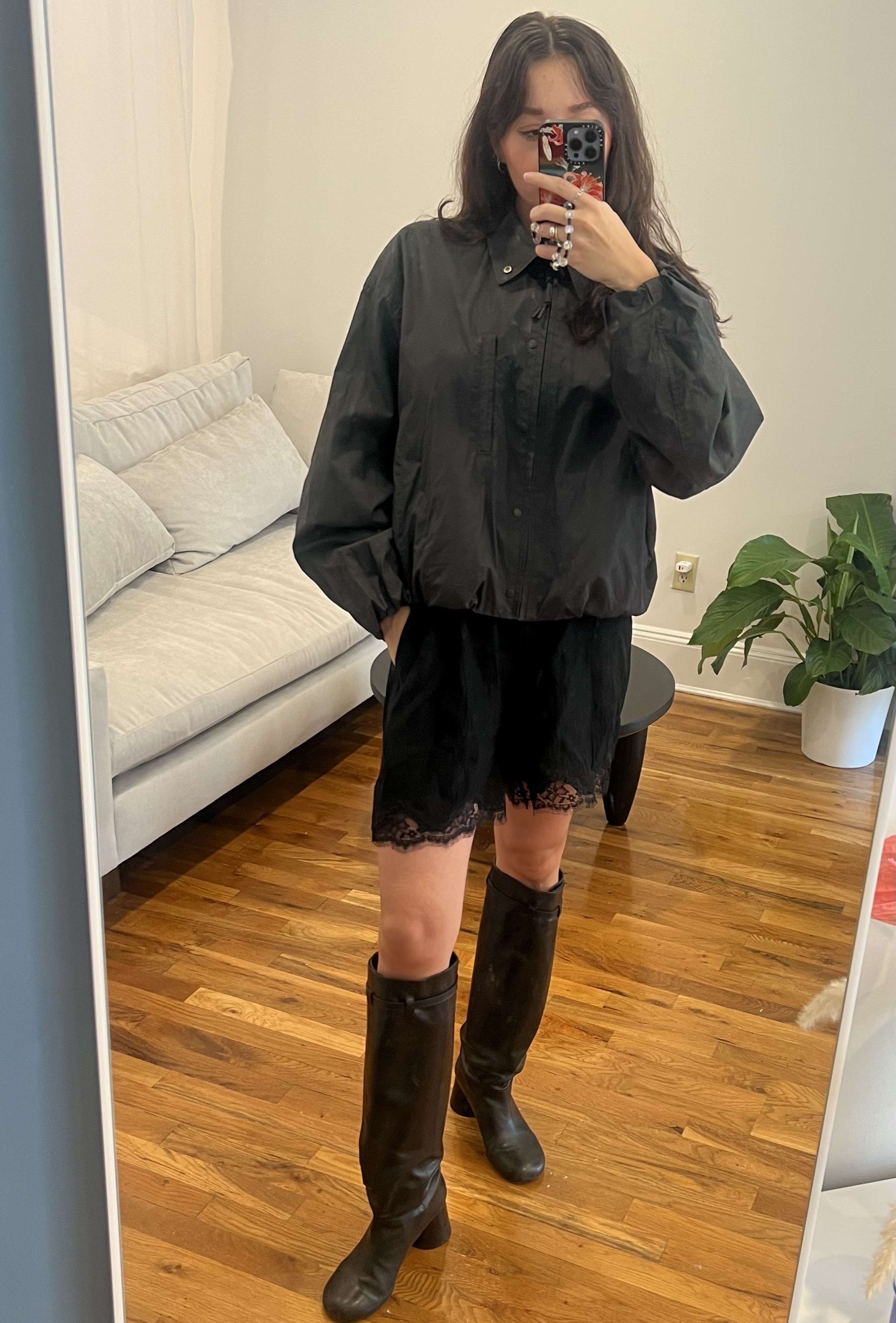 Marie Claire fashion features editor Emma Childs wearing a grey windbreaker jacket, black lace trim shorts, and black knee-high boots
