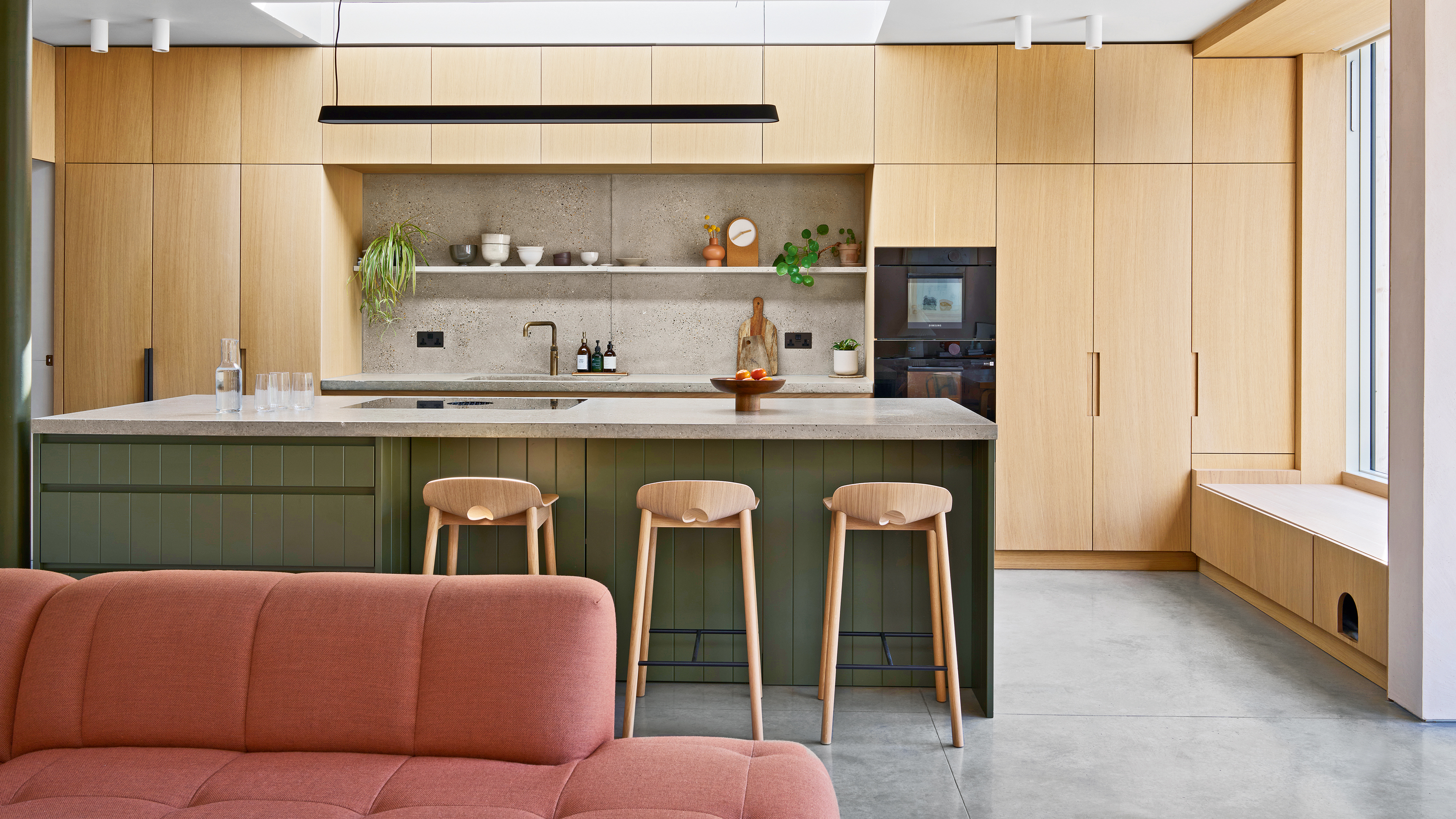 an open plan kitchen, dining and living area a dusky pink sofa and a large kitchen island