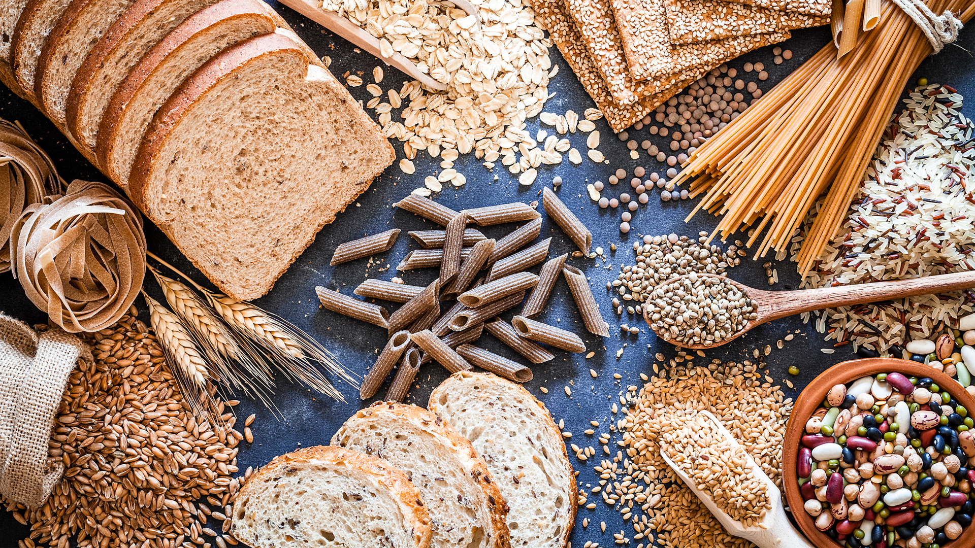 The picture shows a variety of carbohydrates, including pasta, bread, and grains