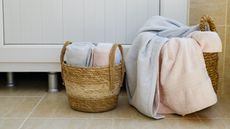 Two wicker baskets with towels on a bathroom floor next to a bathroom vanity
