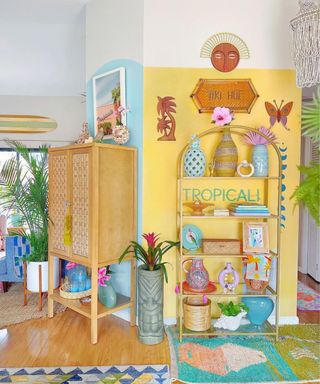 A small entryway with blue and yellow walls, with wooden furniture with decor on it