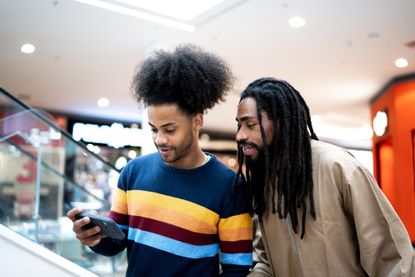 Two men looking at a smartphone at a shopping centre