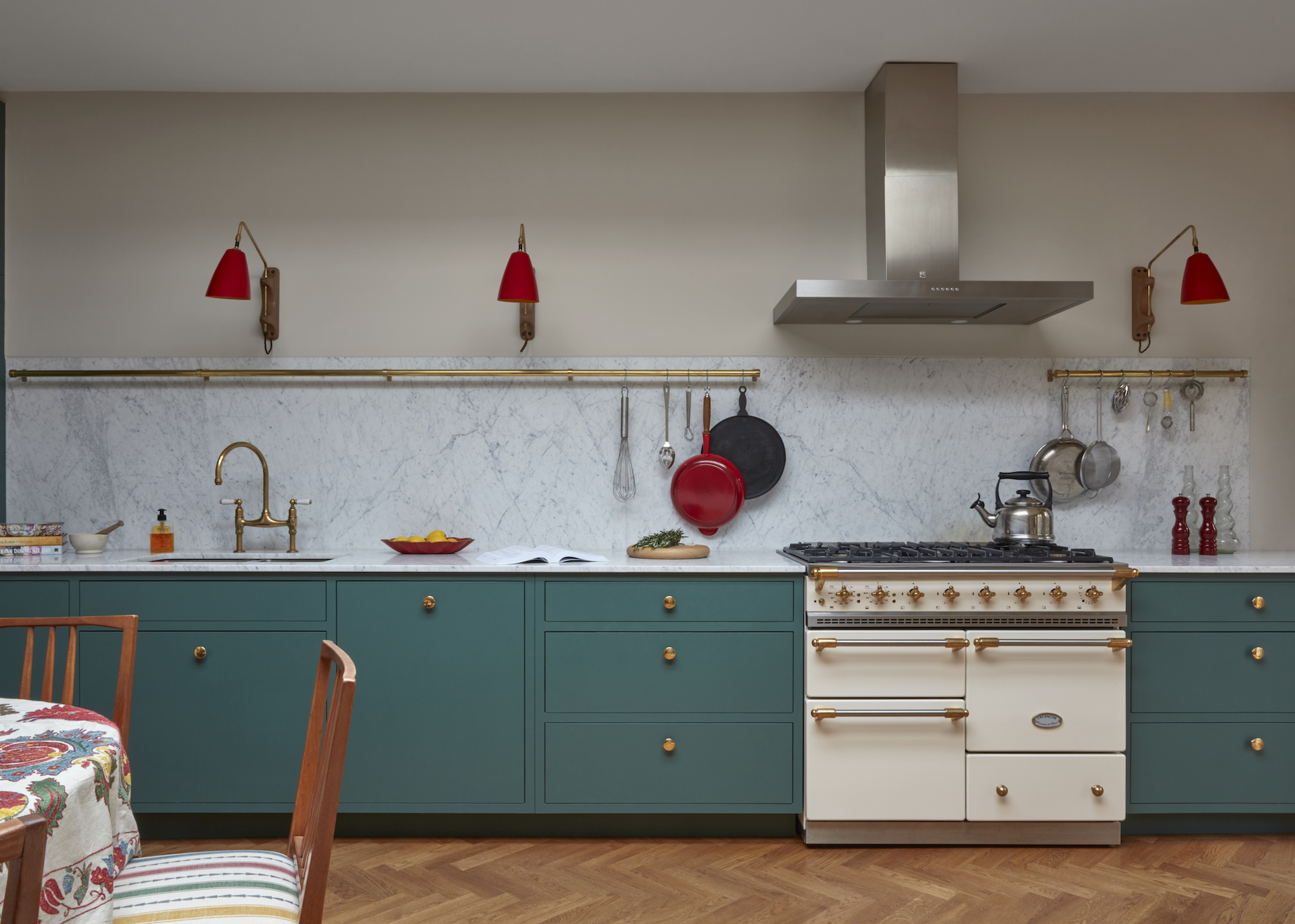 kitchen in teal with wood floors and cream range cooker as well as a view or the corner of a dining table and chair