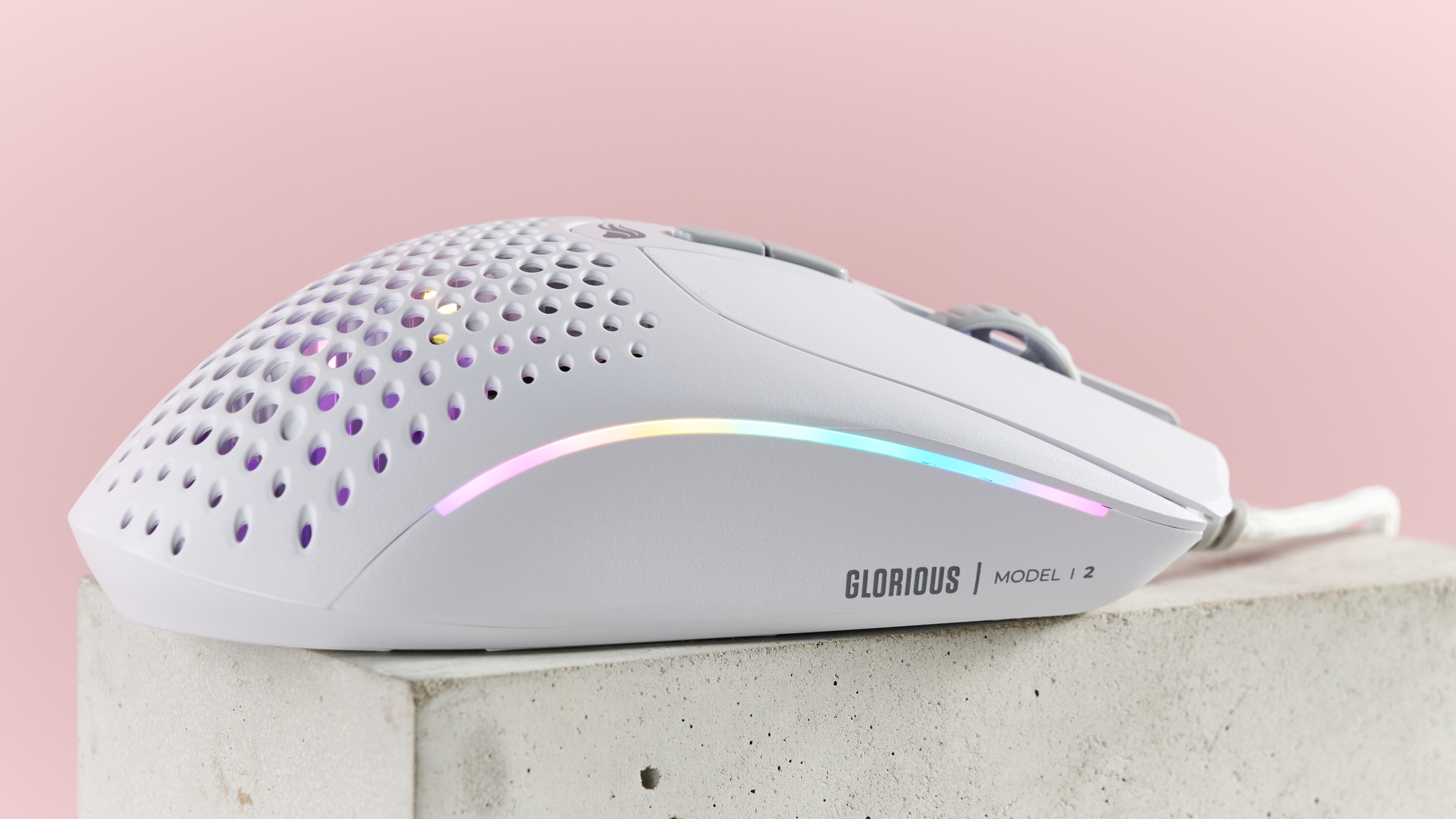 Side view of Glorious Model I 2 with RGB lighting, on plinth with pink background